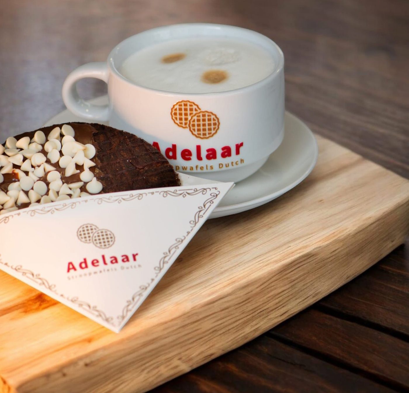 Café y stroopwafel con chispas de chocolate blanco servidos sobre una tabla de madera
